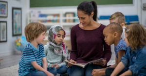 A teacher reading a book with ESL students
