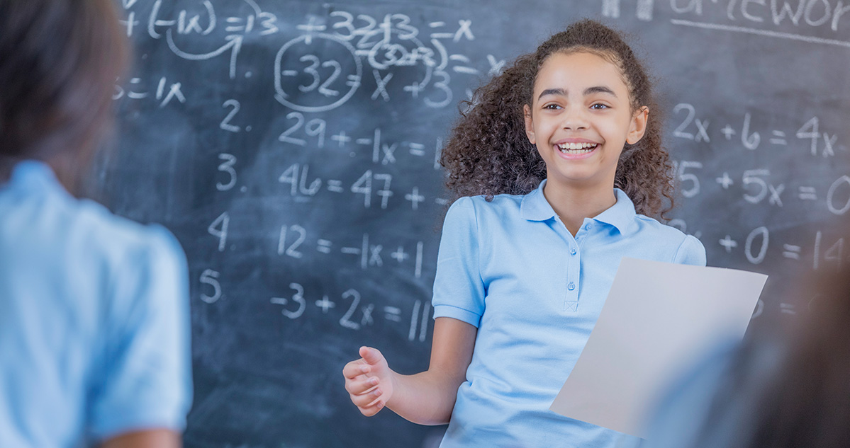 A middle school student doing math problems on a chalkboard