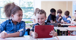 Two kid students using a tablet inside a differentiated classroom.