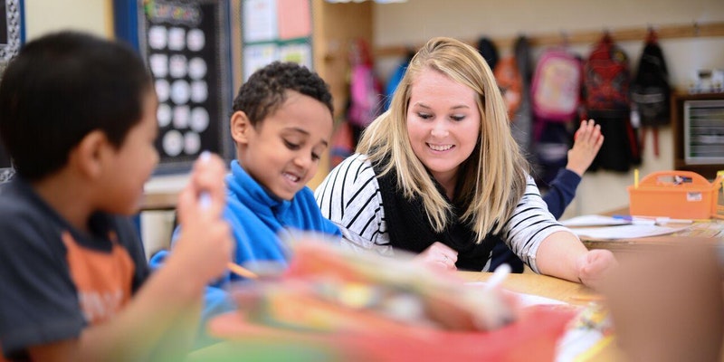 Female teacher helping young students