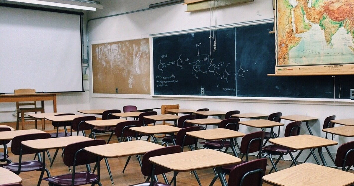 Empty classroom photo with world map hanging on the wall and chalkboard