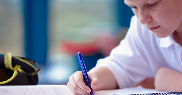 Close up of schoolboy writing in class