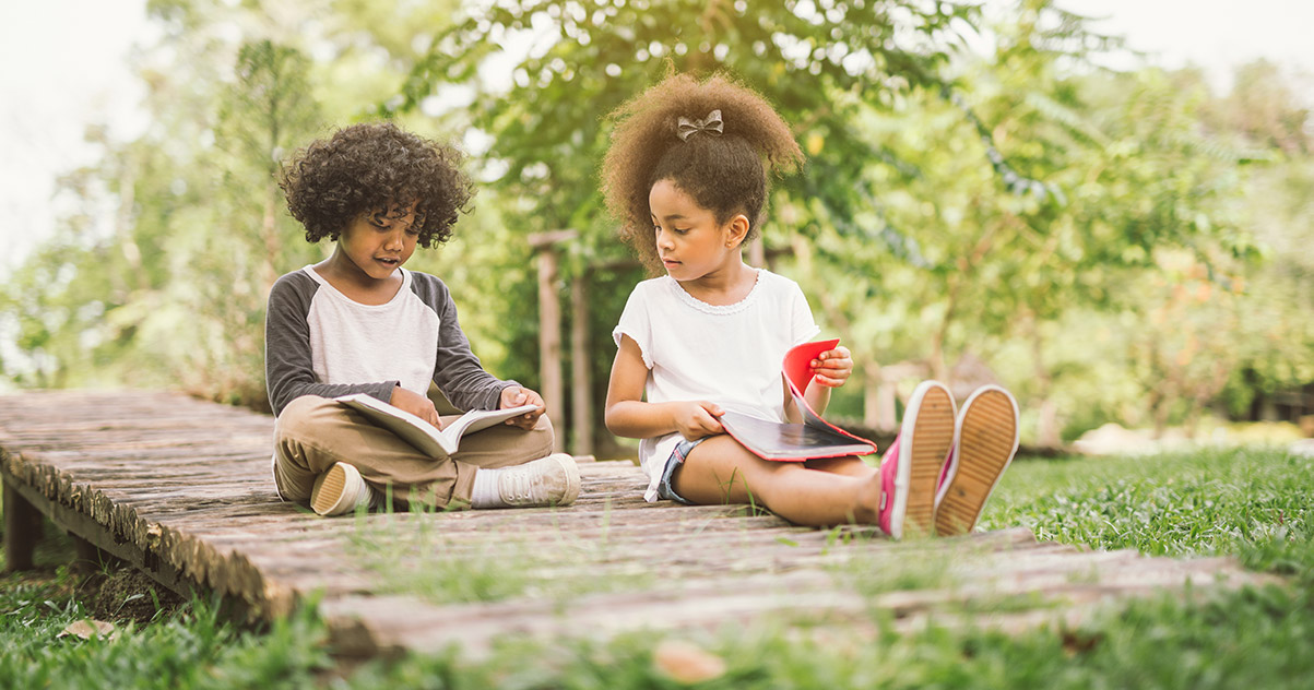Kids reading books together on a beautiful summer day