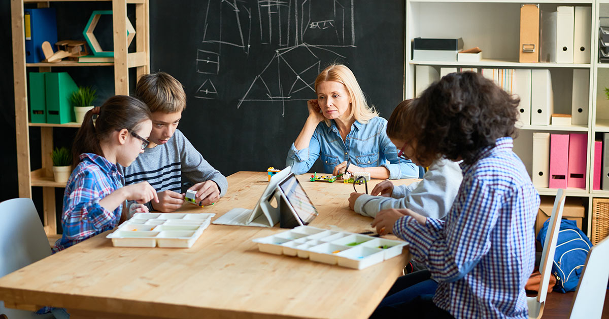 A teacher helping a small group of students with a STEAM project