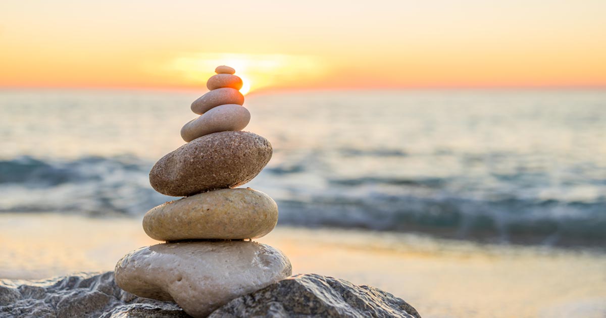 A tower of smooth rocks on the beach at sunrise