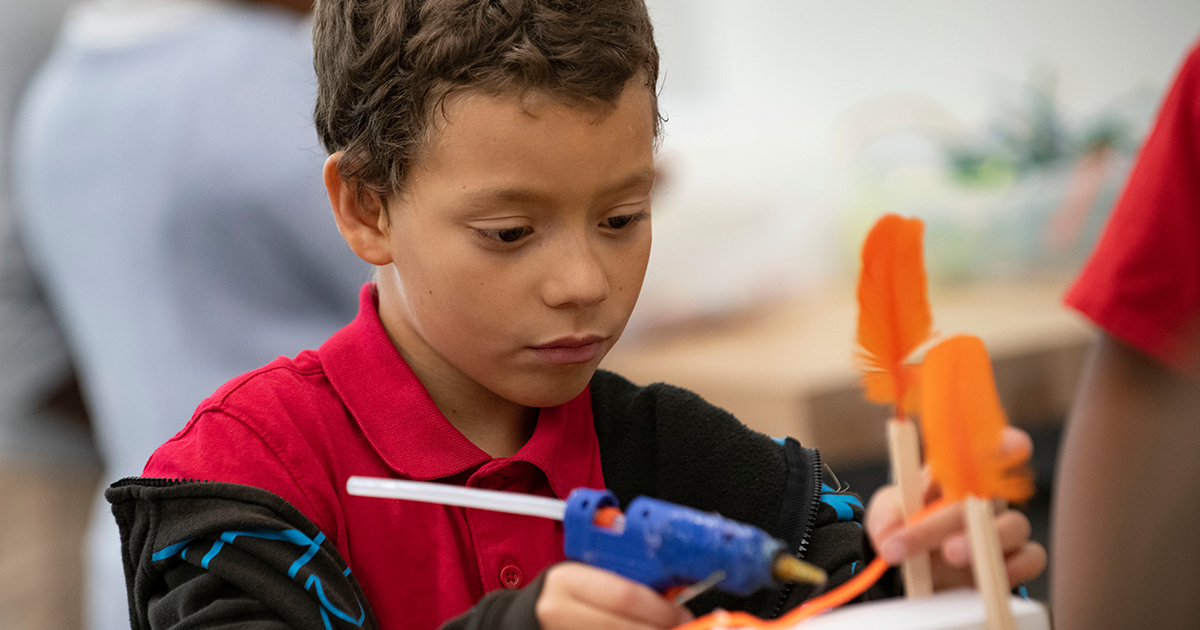 A student working on a STEAM project with a hot glue gun