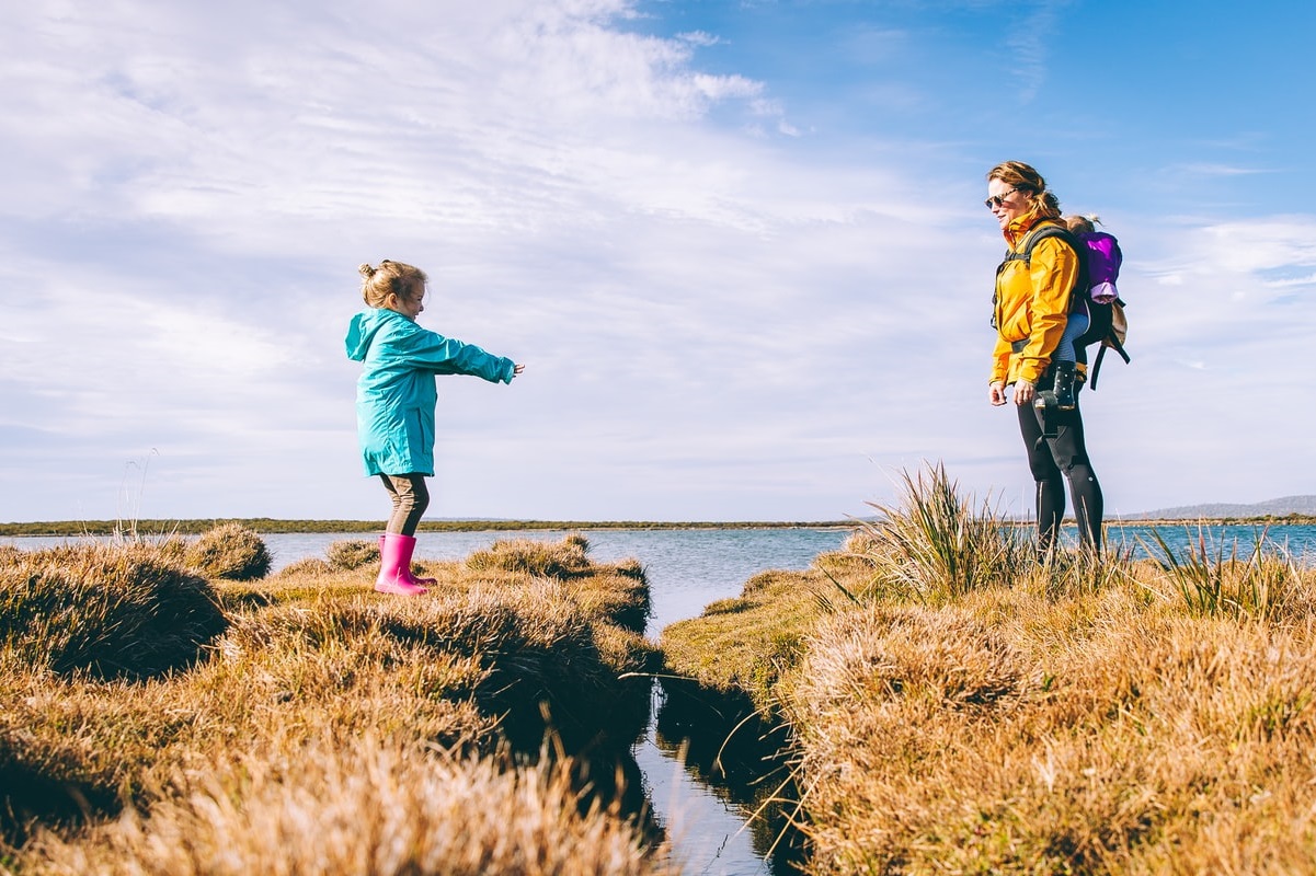 Mother and daughter crossing waterway outdoors