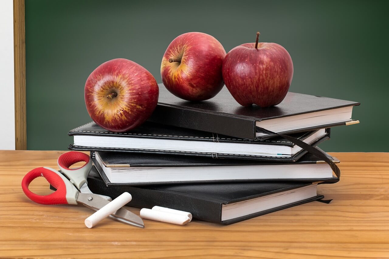 Books, apples, scissors, and school desk