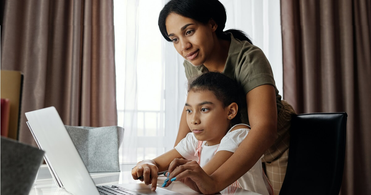 Mother helping her daughter using a laptop