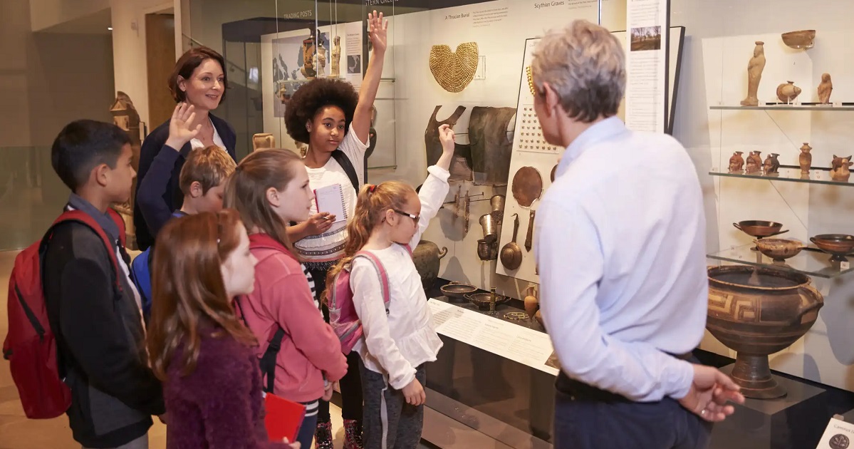 Pupils And Teacher On School Field Trip To Museum With Guide