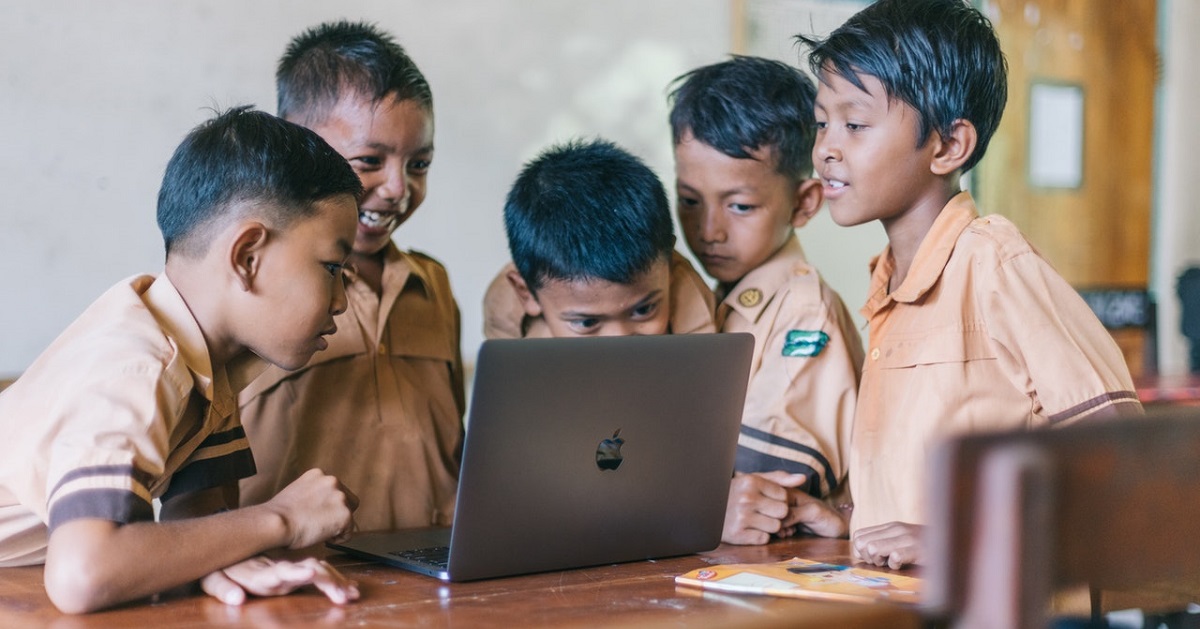 Students huddled around Macbook Pro laptop