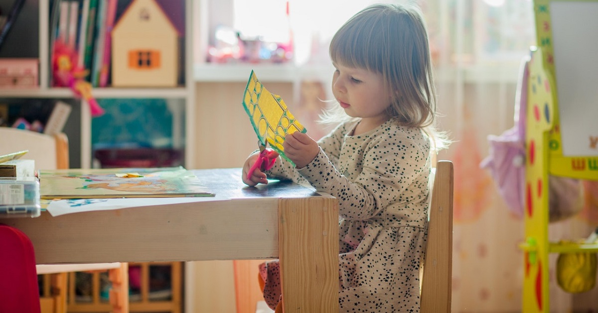 Toddler cutting pieces of colorful construction paper