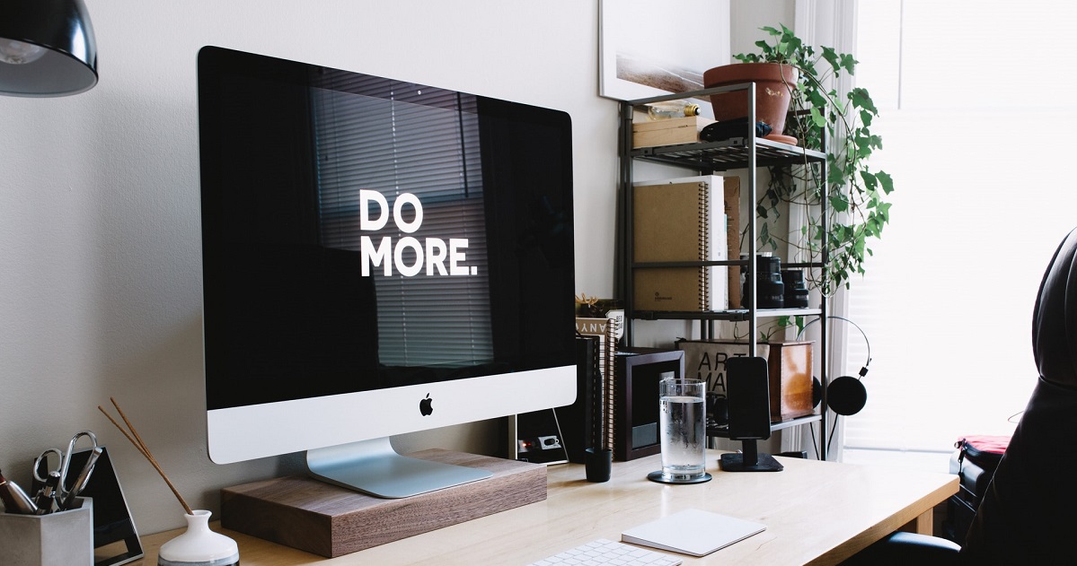 Laptop screen that says DO MORE on desktop in lighted office.
