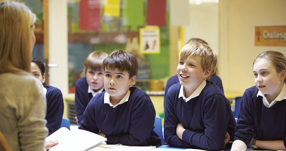 Teacher facing several students who are eager to learn in the classroom