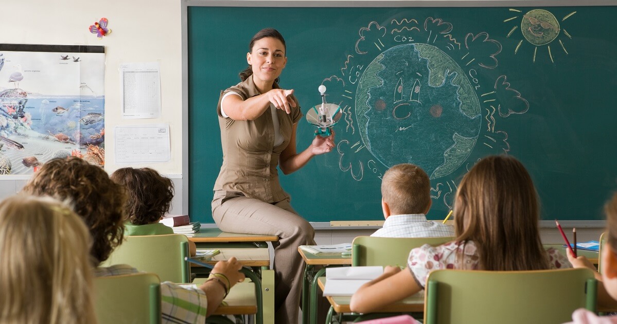 Teacher holding tech gadget while answering student questions about STEM/STEAM